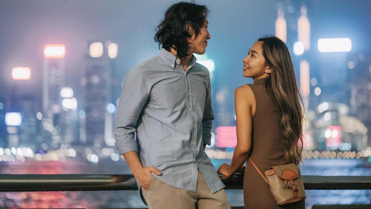 Couple photographed on the Tsim Sha Tsui promenade with the Victoria Harbour skyline behind them during a Hong Kong photoshoot