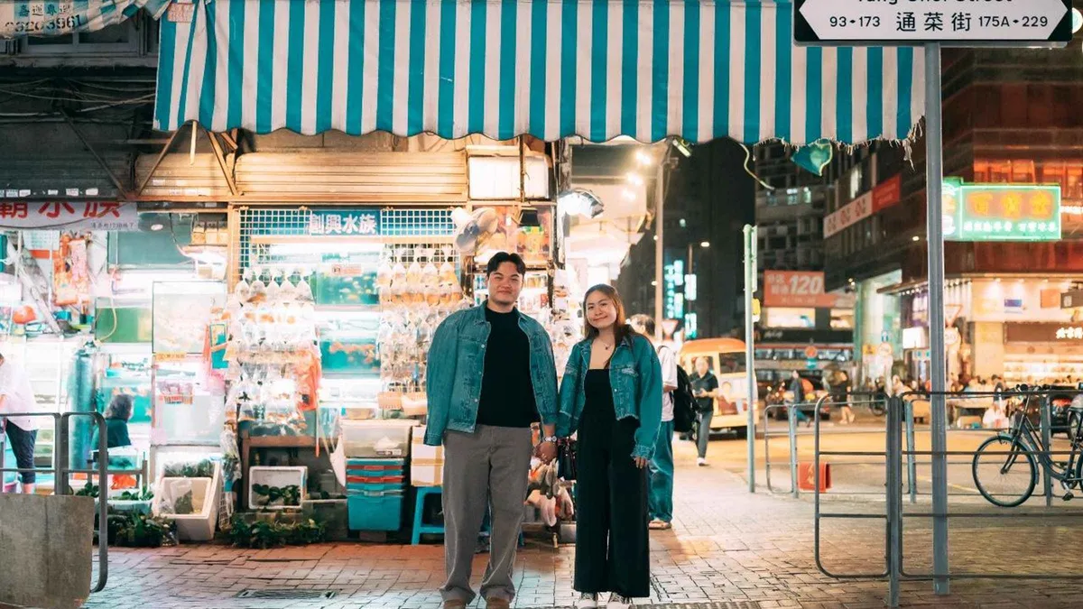 Photographer directing a solo traveller on a neon-lit Mong Kok street during a Hong Kong street photoshoot in Kowloon